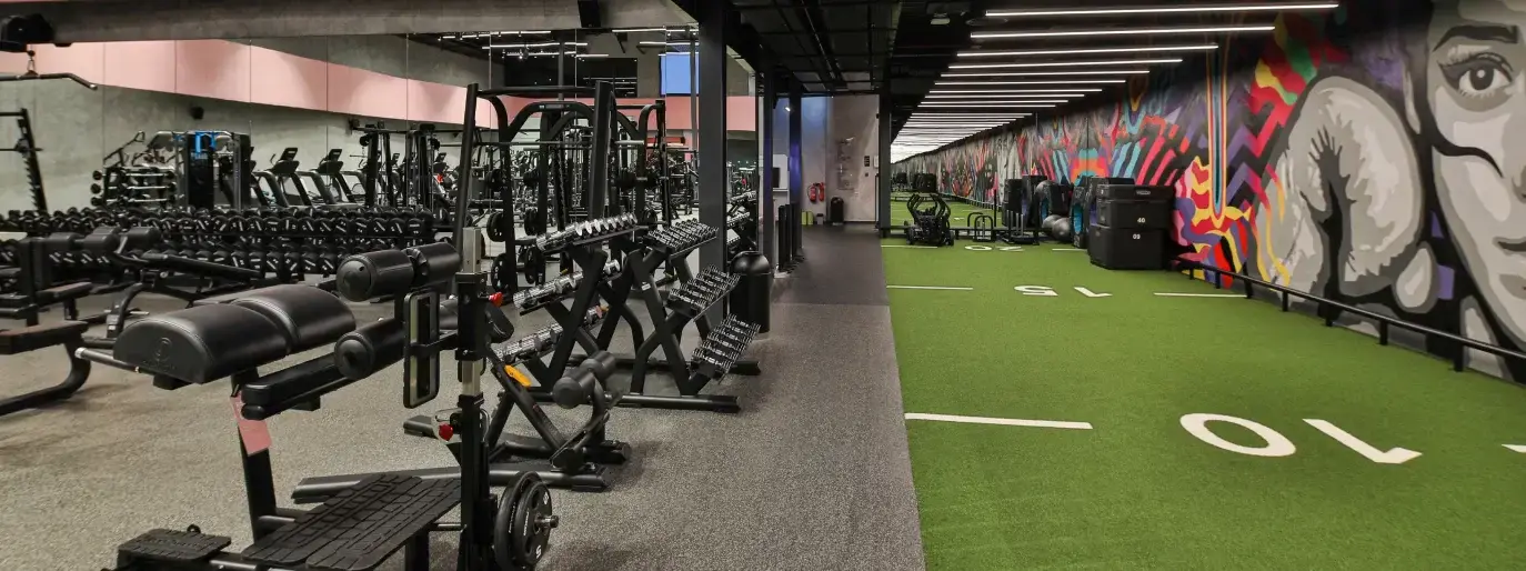FitnGlam Al Quoz gym floor with racks, dumbbells and turf lanes