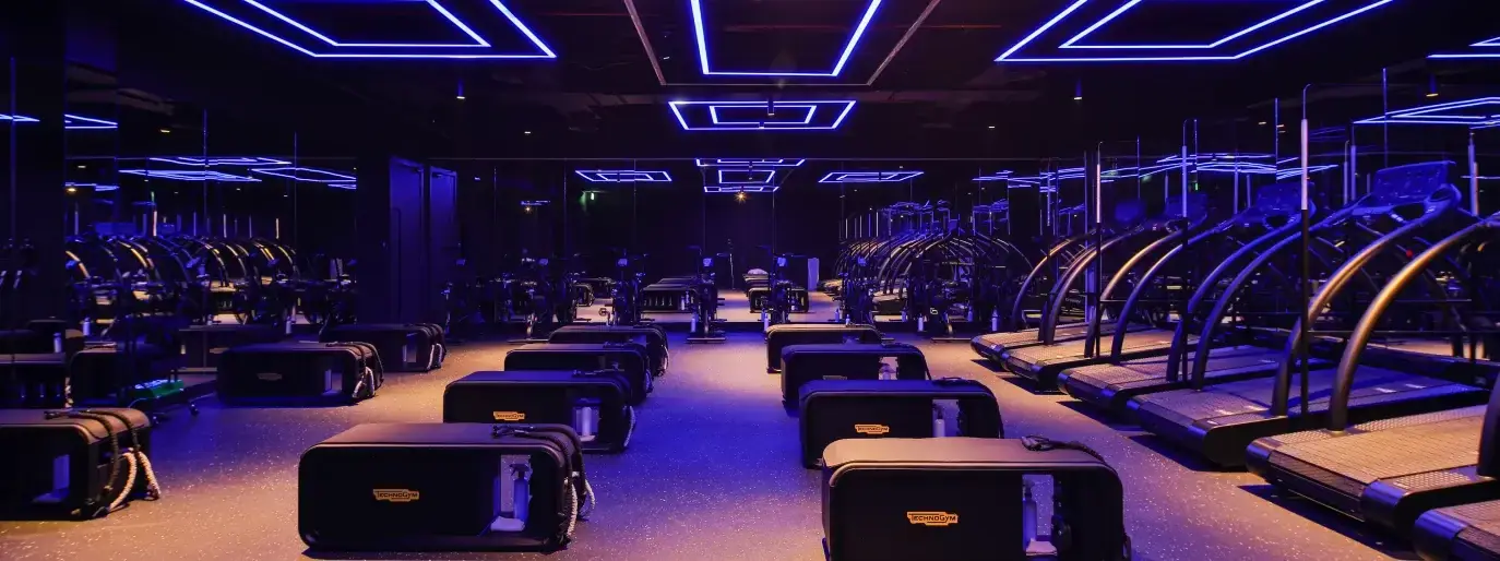 HIIT studio with a row of treadmills under red lighting